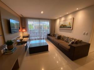 uma sala de estar com um sofá e uma mesa em Apartamento Breezes do Cumbuco - TÉRREO o famoso pé na areia em Cumbuco