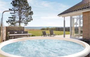 a hot tub on a patio with a table and chairs at Pet Friendly Home In Ebeltoft With House Sea View in Femmøller