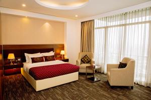 Habitación de hotel con cama, sillas y ventana en Jashore IT Park Hotel and Resort, en Jessore