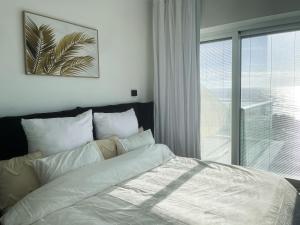 a bedroom with a white bed with a window at Sea Resort in H̱adera