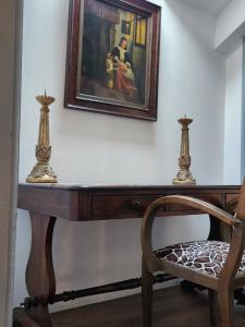 einem Holztisch mit einem Bild an der Wand und einem Stuhl in der Unterkunft Le Phisan in Épinal