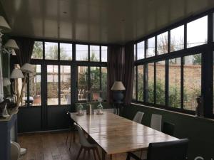 une salle à manger avec une grande table en bois et des fenêtres dans l'établissement Le Logis Cholet 49300 lieu exceptionnel en famille ou amis, à Mazières-en-Mauges