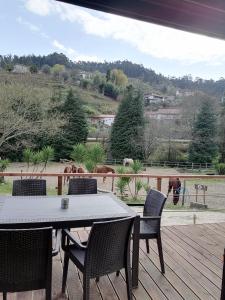 a table and chairs on a deck with horses in the background at Quinta Do Fijo in Arcos de Valdevez