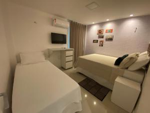 um quarto de hotel com duas camas e uma televisão em Apartamento Breezes do Cumbuco - TÉRREO o famoso pé na areia em Cumbuco