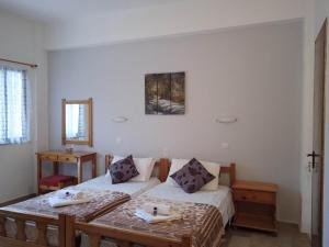 a room with two beds and a table in it at Villa Kaloudis Rooms in Agios Georgios