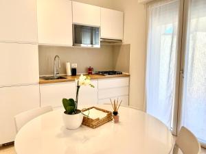 a white kitchen with a white table and white chairs at Suite Claudia in Sirmione +5 photos