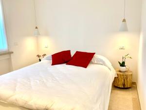 a bedroom with a white bed with two red pillows at Suite Claudia in Sirmione