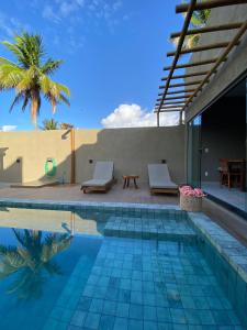 - une piscine avec 2 chaises et un palmier dans l'établissement Nareia Casa Milagres, à São Miguel dos Milagres