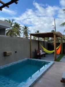 a swimming pool with a hammock next to a house at Nareia Casa Milagres in São Miguel dos Milagres