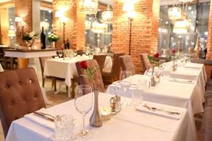a restaurant with white tables and chairs with roses on them at Hotel Achterum Greetsiel in Greetsiel