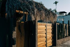 a wooden fence with a wooden gate and a thatch roof at Casa Sirena in Ixtapa