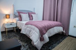 1 dormitorio con 1 cama con sábanas moradas y blancas en Apartamentos MC centro, en Ronda