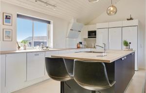 una cucina con armadi bianchi e un'isola con sedie di 8 Bedroom Awesome Home In Thisted a Thisted