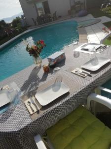 a table with plates and utensils next to a pool at Entre Alpes et Léman in Publier