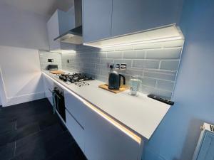 a white kitchen with a stove and a counter top at Modern Luxury 3 bed house in Plymouth