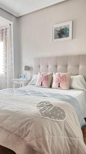 a white bedroom with a large bed with pink pillows at TUDELA CENTRO-Teatro Gaztambide-3 habitac. in Tudela
