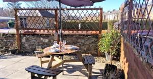 einen Holztisch und Stühle mit Sonnenschirm auf einer Terrasse in der Unterkunft Troon Beachcombers in Troon