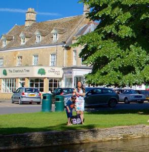 a woman and a child standing in front of a building at Chestnut Bed and Breakfast in Bourton on the Water