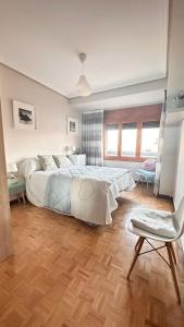 a bedroom with a large white bed and a chair at TUDELA CENTRO-Teatro Gaztambide-3 habitac. in Tudela