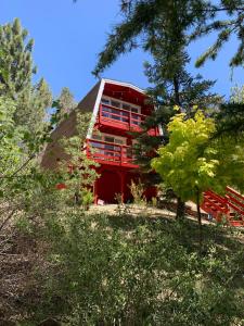 un edificio rojo con balcones rojos en medio de árboles en Maison Solange-Red Barn Farmhouse Style- Moonridge, en Big Bear Lake