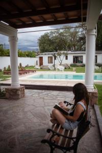 a woman sitting on a bench next to a pool at Tampu in Cachí