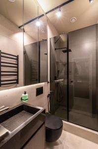 a bathroom with a shower with a sink and a toilet at High five apartments, Most City area in Dnipro