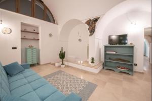 uma sala de estar com um sofá azul e uma televisão em Beautiful Trullo Paleo in Ceglie Messapica em Ceglie Messapica