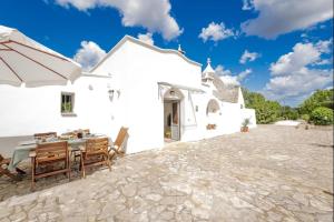 an external view of a white house with a table and chairs at Beautiful Trullo Paleo in Ceglie Messapica in Ceglie Messapica