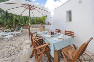 a table with chairs and an umbrella on a patio at Beautiful Trullo Paleo in Ceglie Messapica in Ceglie Messapica