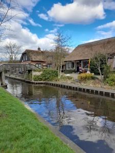 a house with a bridge over a river at Wuivend Riet gelegen op Resort Venetie in Giethoorn