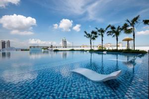 a swimming pool with a white chair in the water at Metropol Serviced Apartment - Bukit Mertajam in Bukit Mertajam
