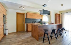 a kitchen with wooden cabinets and bar stools at Amazing Home In Selnica With Kitchen in Selnica