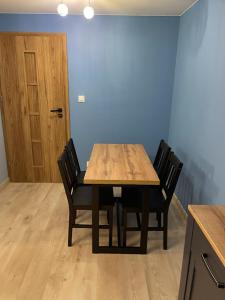 a wooden table with four chairs in a room at Apartament Oksywie II in Gdynia