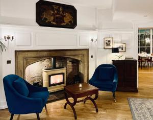 a living room with a fireplace and two blue chairs at The Warwick Arms Hotel in Warwick