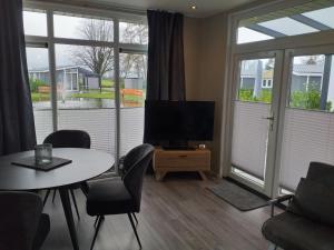 een woonkamer met een televisie en een tafel en stoelen bij Ferienhaus / Chalet / Bungalow am See, Holland, Niederlande, Lathum in Lathum
