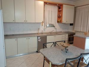 a kitchen with white cabinets and a table with chairs at Fully Furnished Cozy Stay in Thérmi