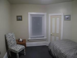 a bedroom with a bed and a chair and a window at Wolseley the heart of the city ! in Winnipeg