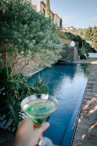 a person holding a drink in front of a pool of water at Boutique Hotel Villa Gala in Cadaqués
