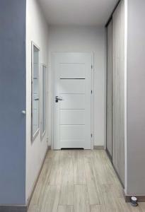 an empty hallway with a white door and wooden floors at Apartament z widokiem na panoramę Gdyni w Modern Tower ATAL in Gdynia