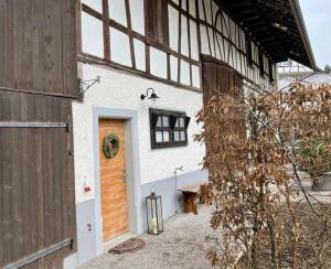 ein weißes Gebäude mit einer Holztür und einer Bank in der Unterkunft Bed & Breakfast Gaetzi in Windlach