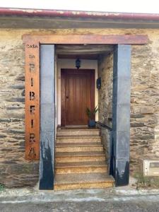 ein Steingebäude mit einer Holztür und einer Treppe in der Unterkunft Casa de Campo - Casa da Ribeira 