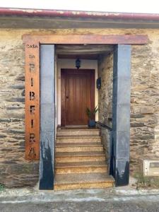 a stone building with a wooden door and stairs at Casa de Campo - Casa da Ribeira in Serapicos
