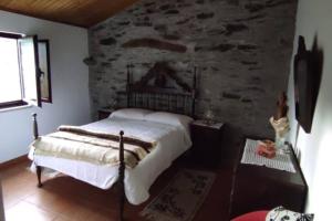 a bedroom with a bed and a stone wall at Casa de Campo - Casa da Ribeira in Serapicos