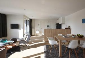 
a kitchen with a table, chairs and a refrigerator at Kustappartementen in Blankenberge
