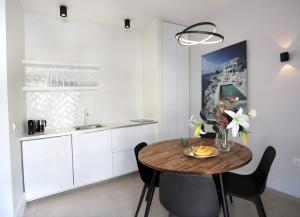 una cocina con armarios blancos y una mesa y sillas de madera. en Junior Unicorn Suite, en Atenas