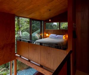 um quarto numa casa na árvore com uma cama numa varanda em Punakaiki Forest Retreat em Punakaiki