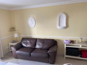 a leather couch in a living room with a clock on the wall at Casa MaGia in Playa de las Americas