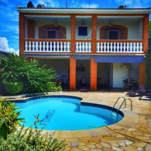 a villa with a swimming pool in front of a house at Estação Brotense - Casa com piscina e fogueira exclusiva in Brotas