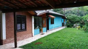 una pequeña casa con un césped verde delante de ella en Pousada Portal do bosque, en Visconde De Maua