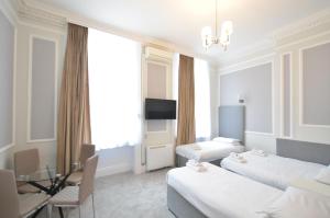 ein Hotelzimmer mit 2 Betten und einem Tisch in der Unterkunft Amber Residence Aparthotel in London